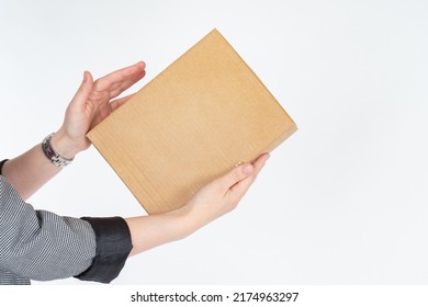 Cardboard Box In Hand. Women's Hands With Gift. Box Symbolizes Gift For Holiday. Girl Holds Out Box Forward. Concept Of Giving Gift Or Parcel. Small Cardbox Without Inscriptions. Blank For Your Logo