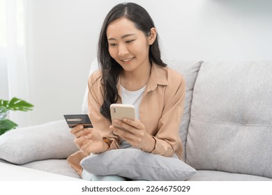 Cardboard box parcel in a trolley, asian young woman using mobile phone with shopping service on market place, website direct buy goods from seller over internet. Online shopping at home, delivery. - Shutterstock ID 2264675029