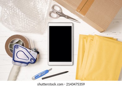 Cardboard Box, Smartphone, Bubble Wrap And Packaging Tools. The Concept Of Packaging Parcels For An Online Store. View From Above. Flat Lay.