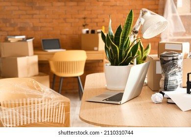 Cardboard Boxes With Belongings And Laptop On Table In Office On Moving Day