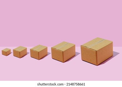 Cardboard boxes of different sizes in a row on a purple background. Parcel delivery concept.