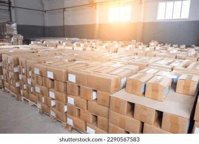 A lot of cardboard boxes with finished products with sweets stand in a warehouse against the backdrop of a window with a sunset. Industry