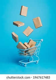 Cardboard Boxes Flying Out Of Shopping Trolley On Vibrant Blue Background. Creative Shop Delivery Service Concept. Banner For Online Shopping Or Retail With Copy Space.