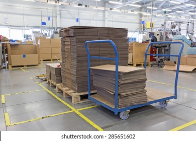 Cardboard boxes are folded in a designated place in the assembly hall. The show of lean management. All potential trademarks are removed.