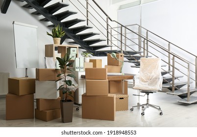 Cardboard boxes and furniture near stairs in office. Moving day - Shutterstock ID 1918948553