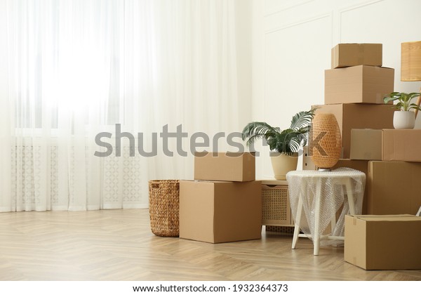 Cardboard boxes and household stuff indoors, space\
for text. Moving day