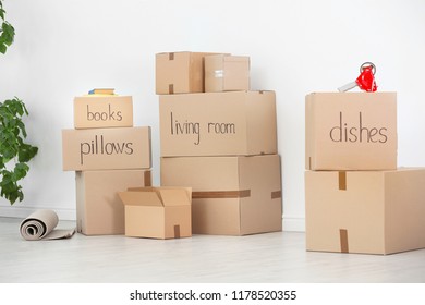 Cardboard boxes and household stuff near white wall indoors. Moving day - Shutterstock ID 1178520355