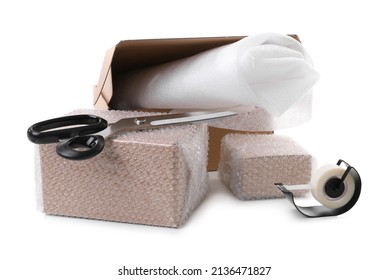 Cardboard boxes packed in bubble wrap, scissors and adhesive tape on white background