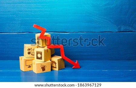 Cardboard boxes and red down arrow. Decline in sales and production volumes. Depressed economy. Low business activity. Economic recession, skepticism and pessimism. Competitiveness of national goods.