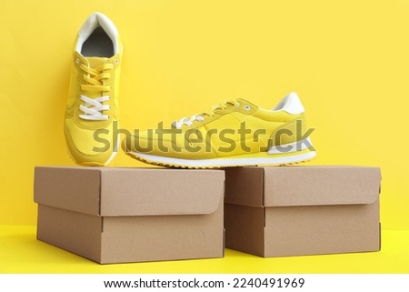 Cardboard boxes with sneakers on yellow background