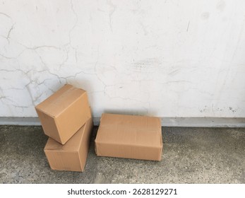 Cardboard boxes stacked near a cracked wall in an outdoor setting