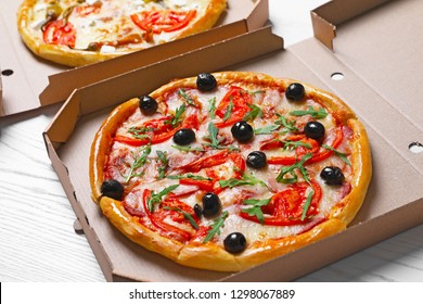 Cardboard boxes with tasty pizzas on wooden table - Powered by Shutterstock