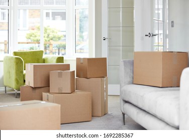 Cardboard carton boxes stack with household belongings in modern house living room. Packed containers on floor in new home.