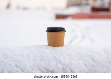 Cardboard coffee Cup in the snow in winter. Hot drink tea or coffee