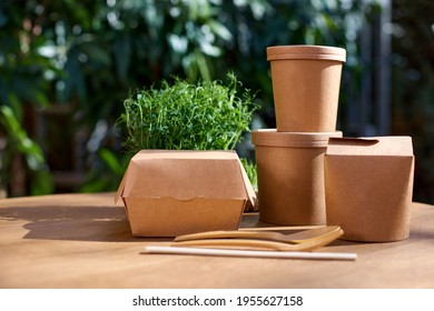 Cardboard containers for food, drinks, items. Copy space. Delivery, takeaway, zero waste, eco production packaging concept, variety of paper takeout containers to client at house and hanging outside.