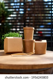 Cardboard Containers For Food, Drinks, Items. Copy Space. Delivery, Takeaway, Zero Waste, Eco Production Packaging Concept, Variety Of Paper Takeout Containers To Client At House And Hanging Outside.