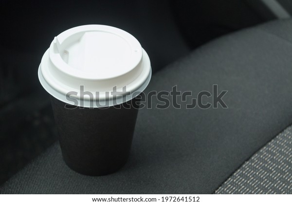 Cardboard cup with coffee on the car seat. Stop
on the road. Morning
coffee.