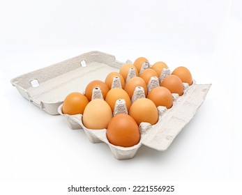 Cardboard egg box with fifteen brown eggs isolated on white background with copy space. Selective focus.