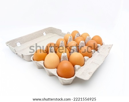 Cardboard egg box with fifteen brown eggs isolated on white background with copy space. Selective focus.