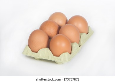 Cardboard egg box with six brown eggs isolated on white.