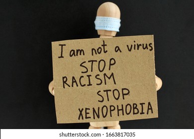 Cardboard Sign With Text In The Hands Of A Wooden Doll Or Mannequin In A Medical Mask. Concept Of Anti Racism, Anti Xenophobia, The Social Situation Around The Coronavirus Or Covid-19.