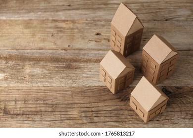 Cardboard toy houses on wooden background. Sale or rental of housing. Neighbors in house. Comfortable life in suburbs.