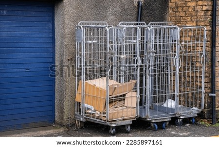 Cardboard trash collected in trolley roll cage at the back of a shop delivery area