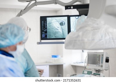 a cardiac surgeon in the operating room, observes on x-ray monitors, a pacemaker installed in a patient. cardiovascular surgery.  - Powered by Shutterstock