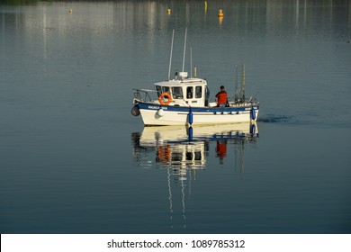 Cardiff Bay, Wales -2018: A Small Fishing Boat With People On Board Making It's Way Across Cardiff Bay In Early Morning Light For A Day's Fishing In The Bristol Channel