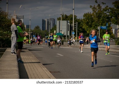 Cardiff Bay, Wales, UK - 09.26.2021: A child runs the Cardiff 10K race, while spectators clap on support.