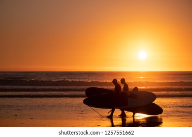 Cardiff By The Sea, California / USA 12/12/2018. Stand up paddle boarders or SUP's carry their gear along the beach at sunset in Cardiff California San Diego.