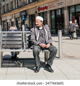 Cardiff, UK. May 2018. A Man Sitting On A Seat, Wearing A Traditional White Taqiyah Or Kufi Cap. 