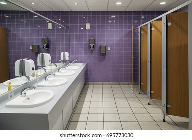 Cardiff, UK: November 13, 2016: Public Bathroom. Ladies Restroom With Cubicles And Sinks And A Purple Tiled Wall. 