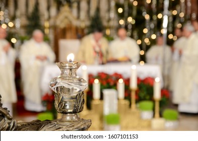 Cardinal And Priest In Front Of The Altar In Catholic Church. Lit Candle. Christmas Midnight Mass In Cathedral. Christianity And Religion.   


