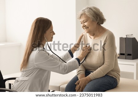 Cardiologist in coat examines older woman in clinic, listen to heartbeat with stethoscope during patient visit. Elderly woman passes heart check-up in hospital. Citizen healthcare services, cardiology