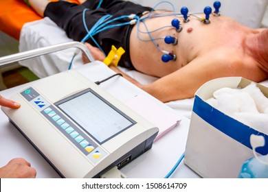 Cardiologist with electrocardiogram equipment is making cardiogram test of patient who is attached with vacuum sensors to the machine. 