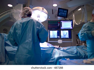A cardiologist implants a heart defibrillator in a patient. The implantable cardioverter defibrillator, ICD, also includes a pacemaker.  Focus is on the fluoroscopy monitors. 
