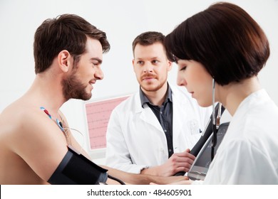 Cardiologist and nurse assist the patient during a cardiac stress test examination