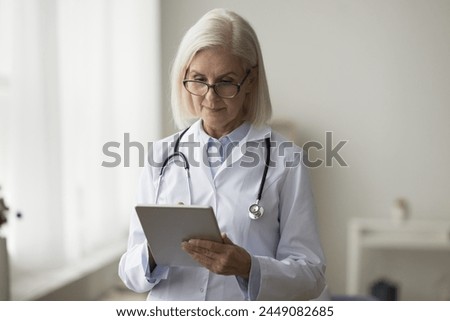 Cardiologist using digital tablet at workplace, accessing patient electronic health records to review medical history, lab result, learning data and meds lists. Workflow of therapist using modern tech