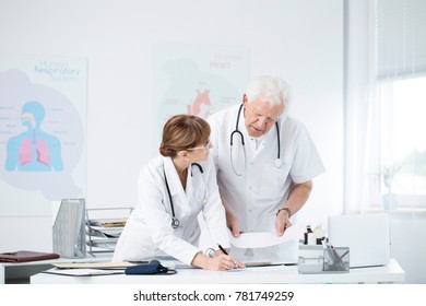 Cardiologists Discussing Patient's Case In Hospital's Office With Poster And Desk