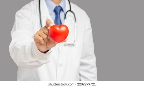 Cardiology Concept. Close-up Of Hand Doctor Holding A Red Heart Shape While Standing In The Hospital. Space For Text. Close-up Photo. Health And Medical Conceptual