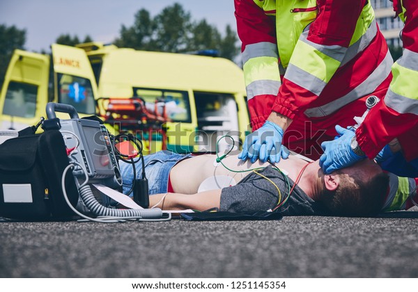 Cardiopulmonary resuscitation.\
Rescue team (doctor and a paramedic) resuscitating the man on the\
road.