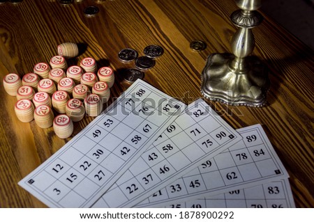 Cards and barrels with numbers for Russian lotto on a wooden table by candlelight.