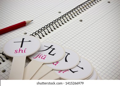 cards with Chinese transcription numbers are on a notebook with a red pencil