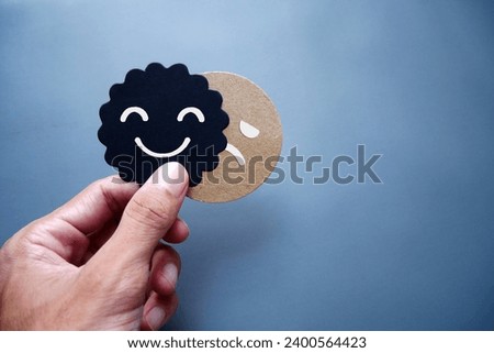 Cards sad face hiding behind happy face with copy space. Concept of introversion, bipolar, depression, mental health, split personality, mood swings.