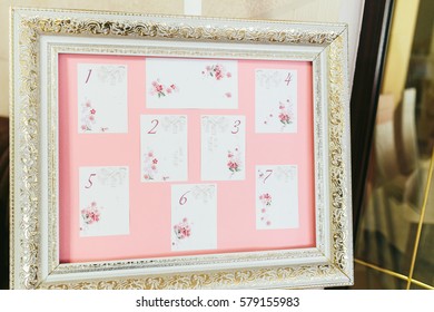 Cards With Wedding Table Plan Put On Pink Background In Golden Frame