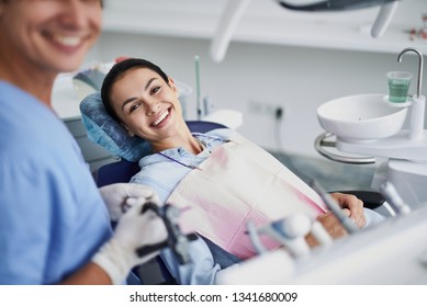 I care about my teeth. Portrait of charming girl sitting in dentist chair while looking at camera and smiling