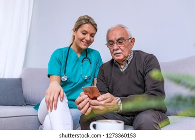 Care aid helping senior man learning to use cell phone. Young caregiver teaching senior man to handle with mobile phone at home. Photo of elderly man with her caregiver - Powered by Shutterstock