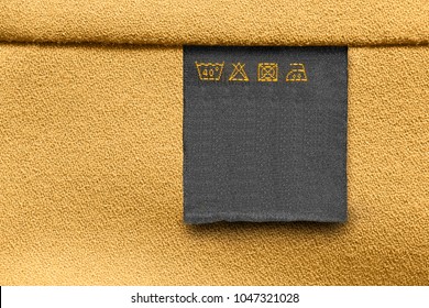 Care Clothes Label On Yellow Textile Background Closeup