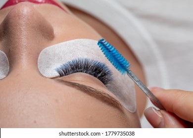 Care of Eyelash Extension with blue brush. Lashes. Woman Eyes with Long Eyelashes in diferent color.